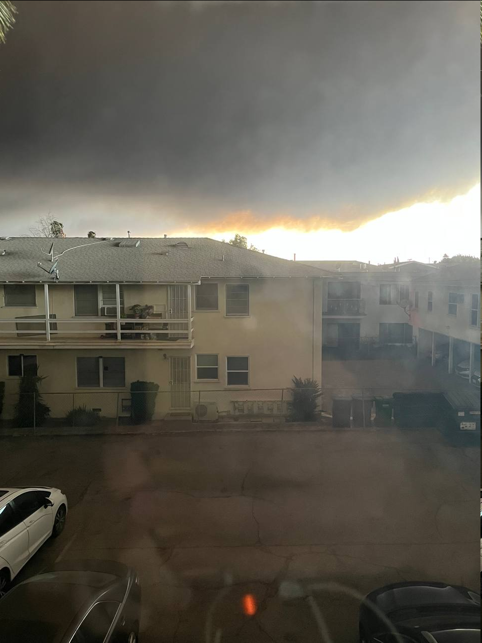 A huge smoke cloud covers most of the sky above an apartment building complex.