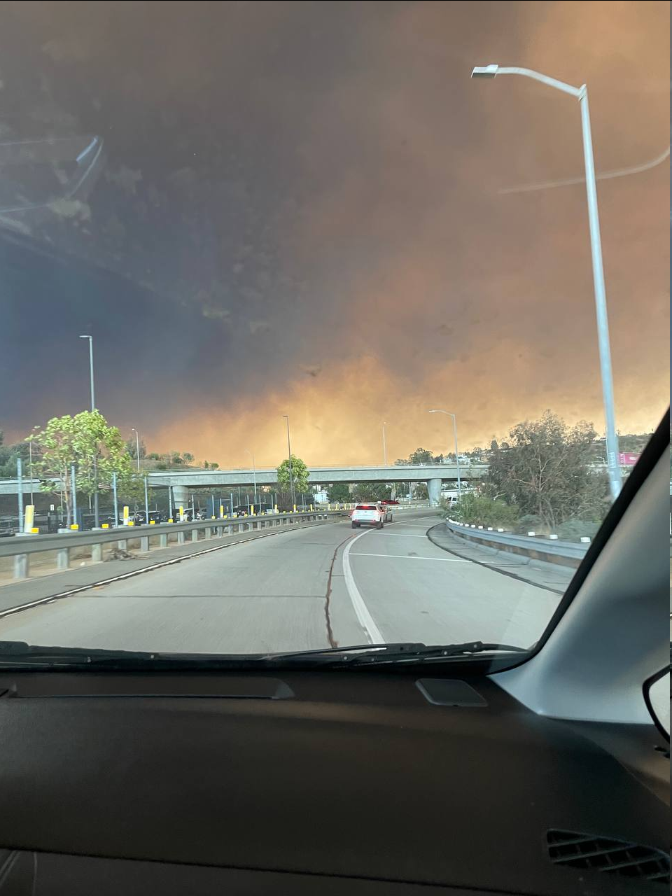 A smoke filled sky above freeways, taken from inside a car on the road.
